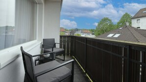 A balcony with a table and chairs, a view of neighboring houses, and a clear sky. - StayBaran XL - 6 Betten I 3 Schlafzimmer I Parkplatz I (Essen)