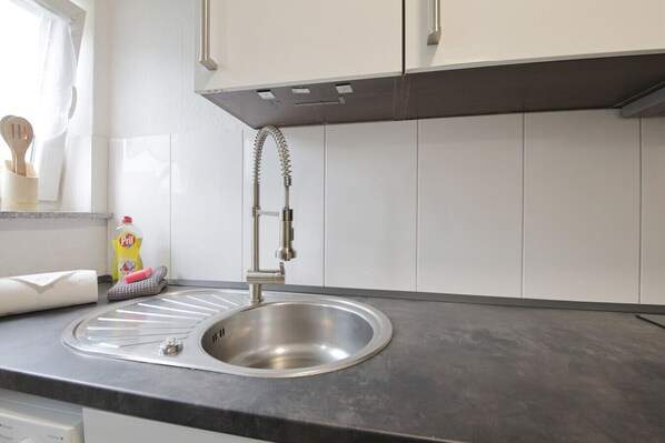 A modern kitchen with a stainless steel sink, a dish soap bottle, and a dish rack.