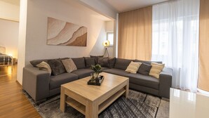A modern living room with a sectional sofa, a wooden coffee table, and a floor lamp. - StayBaran XL - 6 Betten I 3 Schlafzimmer I Parkplatz I (Essen)