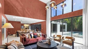 Una sala de estar moderna con un sofá grande, una mesa de centro y un área de comedor al fondo.