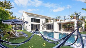 Una casa moderna con piscina, hamaca y zona de patio.