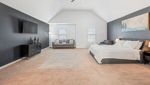 Un dormitorio con cama, sofá, televisión y ventilador de techo.