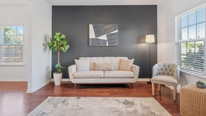 Una sala de estar con sofá, sillón y un cuadro abstracto de gran tamaño en la pared.