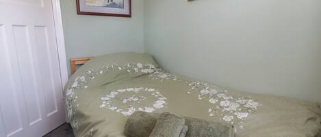 Un dormitorio con una cama, una puerta y dos cuadros en la pared.