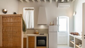 Eine kompakte Küche mit Einbauofen, Kühlschrank und einem Fenster mit Vorhängen.
