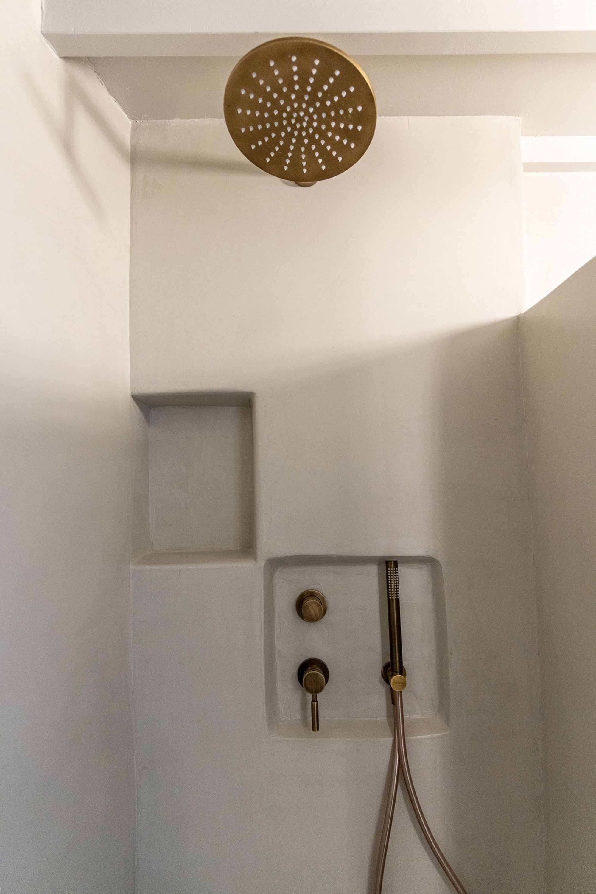 Eine Dusche mit Brausekopf und Armaturen in Gold.