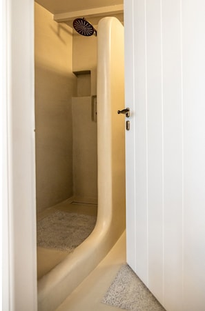A bathroom with a curved shower, a towel rack, and a door with a handle.