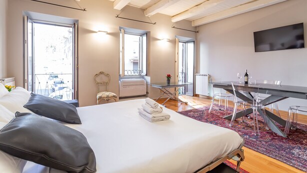 Una habitación de hotel moderna con una cama grande, una mesa de comedor y un televisor montado en la pared.