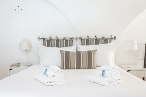 A neatly made bed with striped pillows, two bedside tables with lamps, and towels on the bed. - Trastevere Vintage Artistic Loft (Roma)