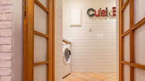 Une buanderie équipée d’un lave-linge, d’un porte-serviettes et d’une pancarte indiquant « CUISINE ».