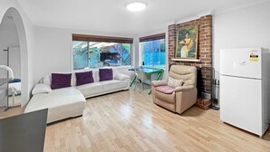 Un salon moderne comprenant un canapé, un fauteuil inclinable, une table à manger et un réfrigérateur.
