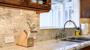 A kitchen with granite countertops, a knife block, a sink, and wooden cabinets. - Bright Family Getaway Large Backyard Oasis Patio (Santa Ana)