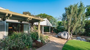A house with a covered porch, a stone pathway, and a well-maintained garden with a large tree and various shrubs. - Bright Family Getaway Large Backyard Oasis Patio (Santa Ana)