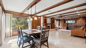 A spacious dining area with a large wooden table and chairs, a kitchen area with wooden cabinets, and a living room with a sofa. - Bright Family Getaway Large Backyard Oasis Patio (Santa Ana)