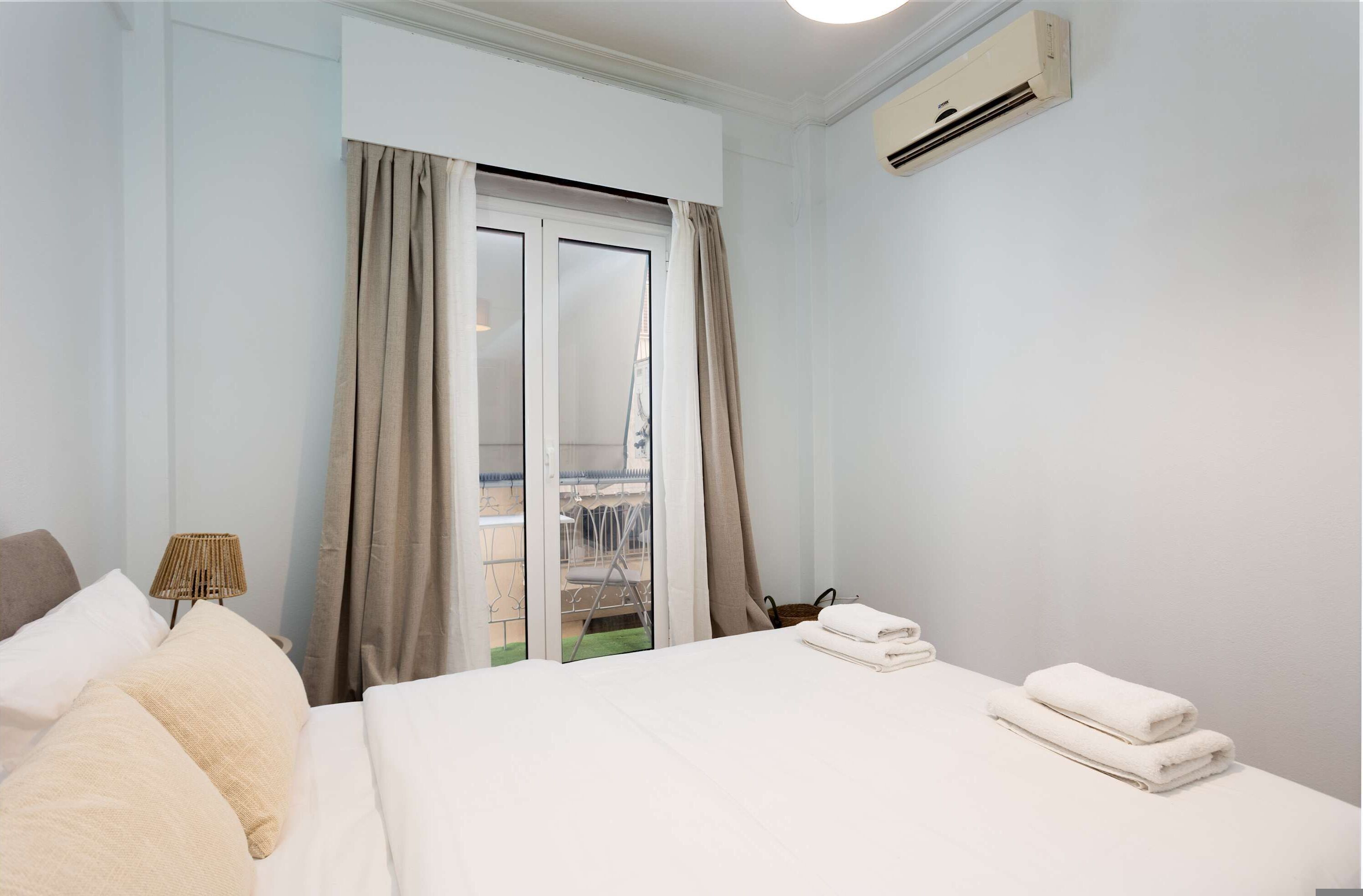 Hotelkamer met een bed, een raam met gordijnen, een airconditioning en uitzicht op een buitenruimte.