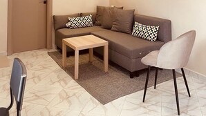 Uma sala de estar moderna com um sofá, uma mesa de centro, uma poltrona e uma porta.