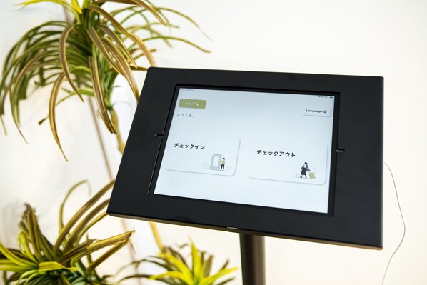 Ein digitales Kiosk mit japanischem Text, umgeben von Topfpflanzen.