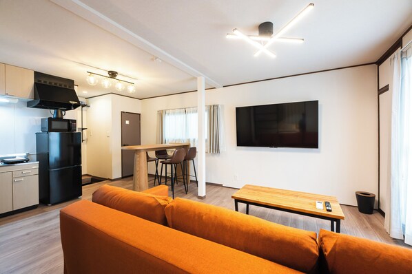 A modern living space with a kitchen, dining area, and a large flat-screen TV mounted on the wall. - Ojanse Hakata (Fukuoka)