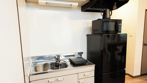 A compact kitchen with a sink, a black microwave, and a black refrigerator.