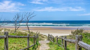 A wooden pathway leading to a beach with ocean views.