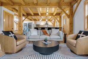 Un salon chaleureux avec un plafond en bois, une table basse ronde et deux canapés en cuir agrémentés de coussins.