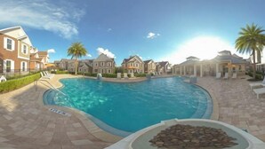 A swimming pool surrounded by houses, a clear sky, and a stone feature. - Summerville Resort 5 Bedroom Vacation Home 2620 (Kissimmee)