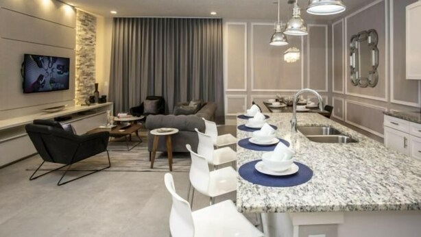 A modern kitchen with a granite countertop, white bar stools, and pendant lighting. - Summerville Resort 5 Bedroom Vacation Home 2620 (Kissimmee)