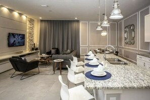A modern kitchen with a granite countertop, white bar stools, and pendant lighting. - Summerville Resort 5 Bedroom Vacation Home 2620 (Kissimmee)
