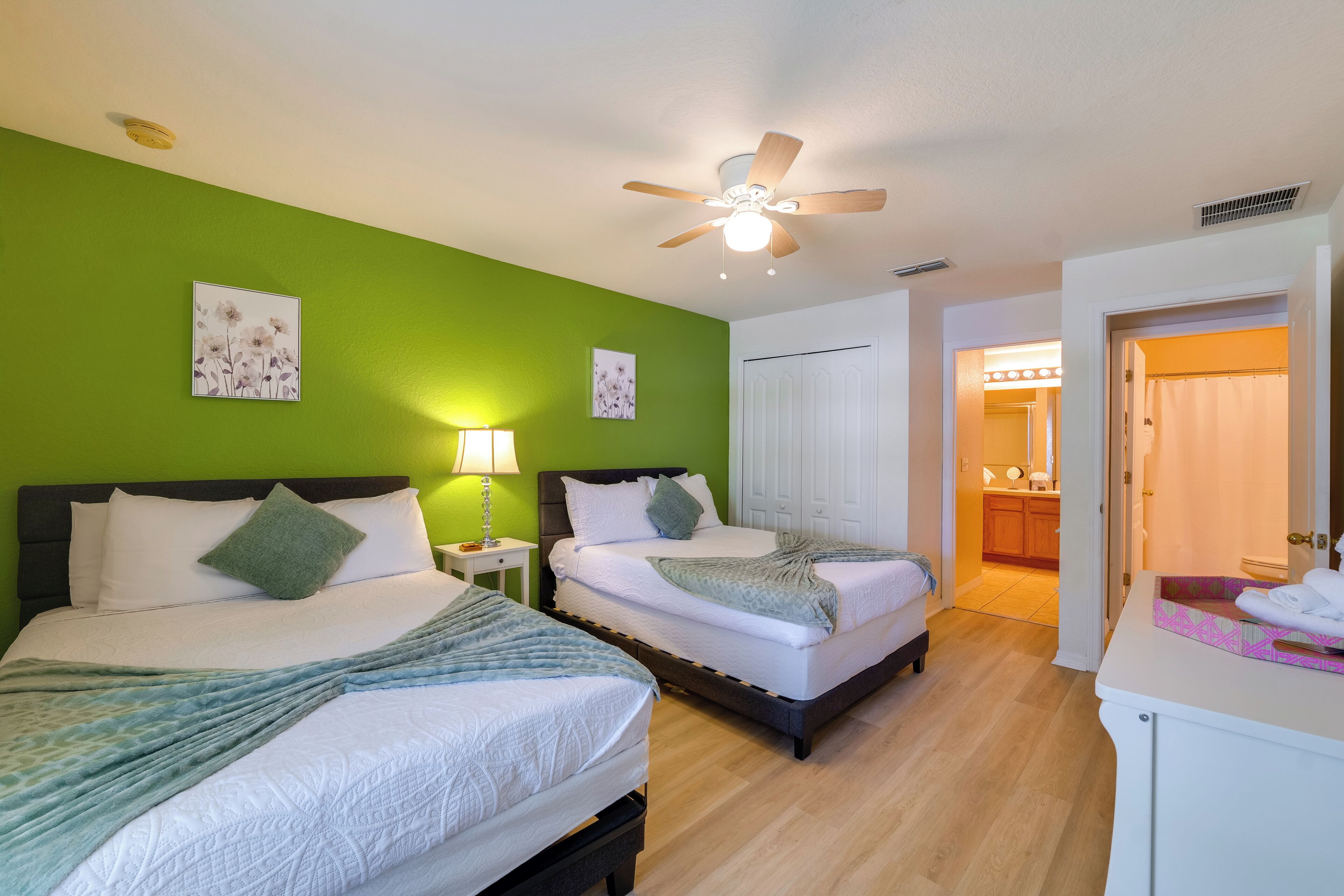 A hotel room with two beds, a ceiling fan, and a bathroom visible through an open door.