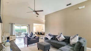A living room with two grey sofas, a small ottoman, a table with a decorative item, and a ceiling fan. - Peaceful Clermont Gem w/ Pool, 9 Mi to Disney! (Clermont)