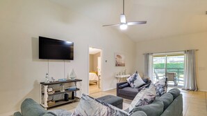 A living room with a large flat-screen TV, a ceiling fan, and a sofa with patterned cushions. - Peaceful Clermont Gem w/ Pool, 9 Mi to Disney! (Clermont)