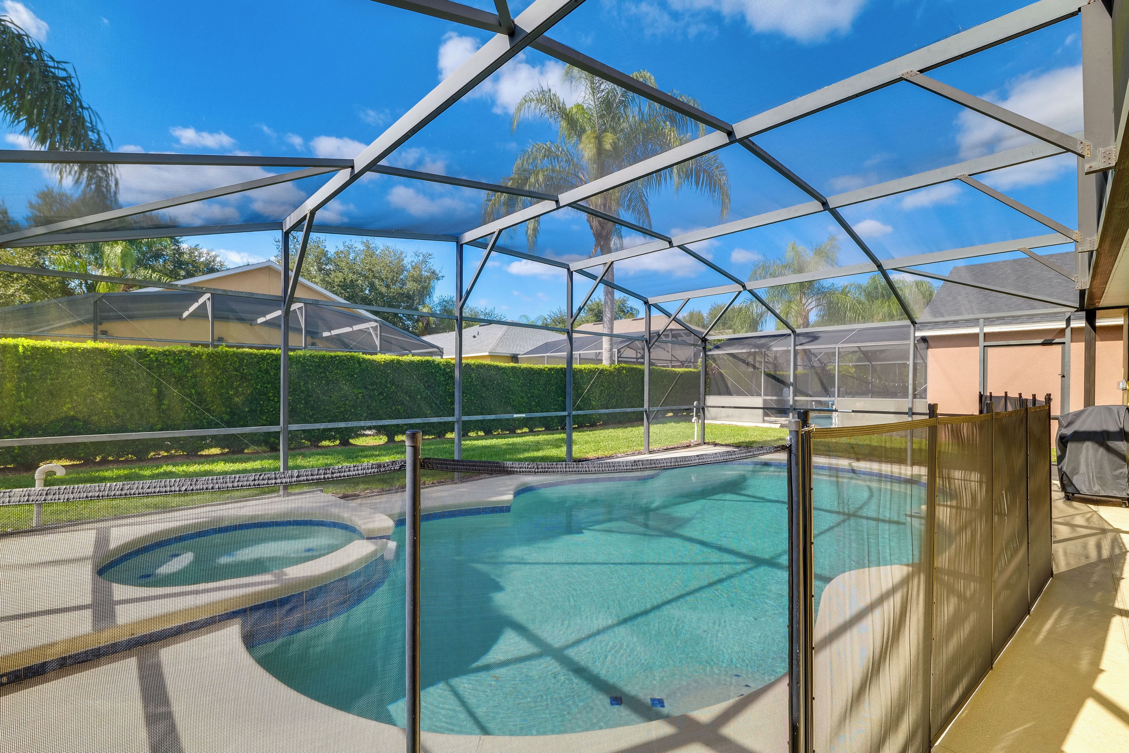 A covered swimming pool with a view of the surrounding landscape, including a house and greenery.