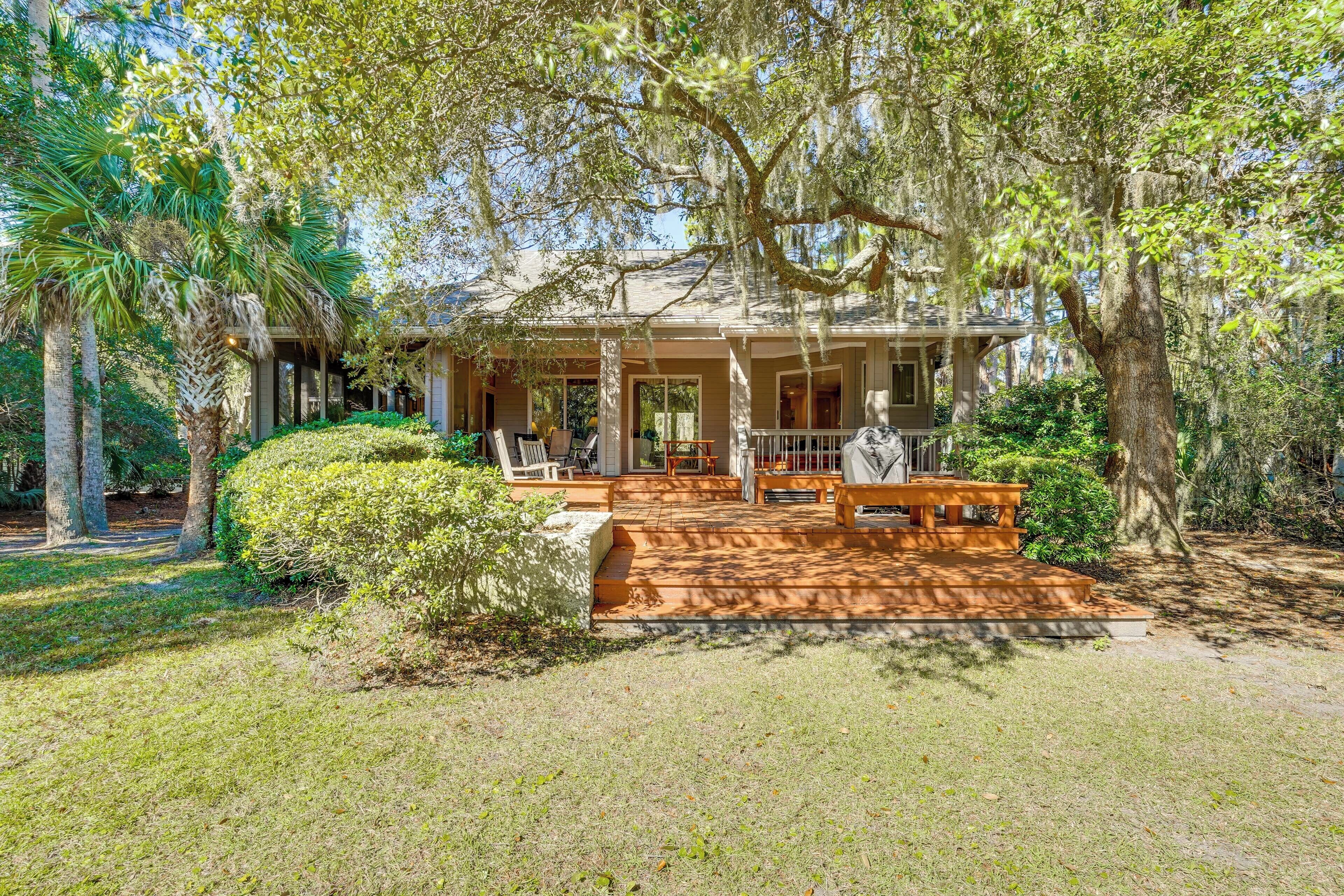 A house with a porch, surrounded by trees and a lawn.