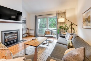 Un salon avec une cheminée, un canapé, une table basse et un téléviseur.