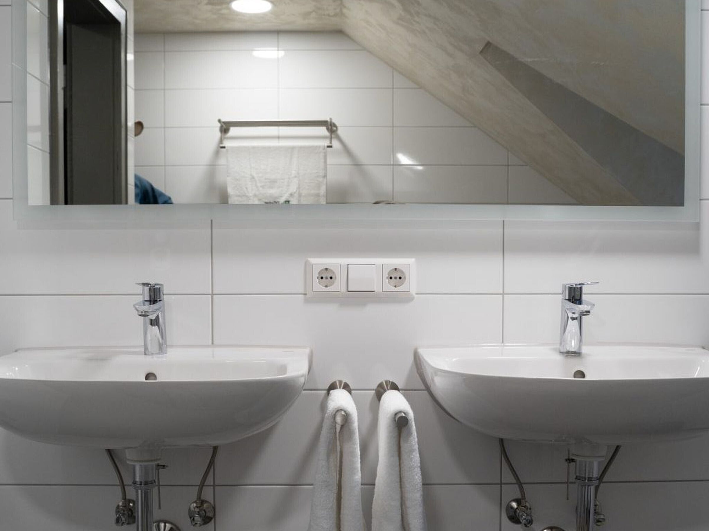 Une salle de bain avec deux lavabos, un miroir et un porte-serviettes.