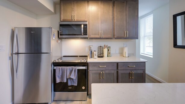 A modern kitchen with stainless steel appliances, wooden cabinets, and a marble countertop. - 1 Mi to University of Cincinnati: 3rd-floor Condo! (Cincinnati)