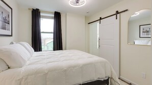 A bedroom with a bed, a ceiling fan, a window with curtains, a door, and a mirror on the wall. - 1 Mi to University of Cincinnati: 3rd-floor Condo! (Cincinnati)