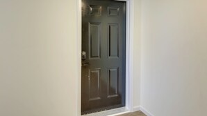 A closed dark-colored door with a white frame, a doorknob, and a small electronic device mounted on the wall beside it. - 1 Mi to University of Cincinnati: 3rd-floor Condo! (Cincinnati)
