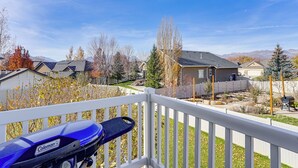 A blue motorcycle on a balcony with a view of a residential neighborhood and mountains in the background. - Park City Area Lodge: 9 Mi to Timber Lakes (Heber City)