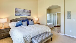A bedroom with a large bed, two bedside tables, a bench, a painting, and a bathroom visible through an archway. - Park City Area Lodge: 9 Mi to Timber Lakes (Heber City)