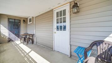 A covered porch with a door, a table, and two chairs.