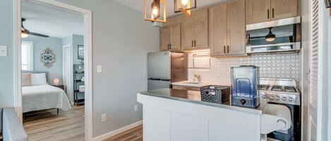 A modern kitchen with wooden cabinets, a stainless steel refrigerator, a built-in oven, and a coffee maker.