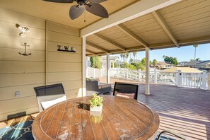 A covered outdoor patio with a round wooden table, chairs, and a small plant.