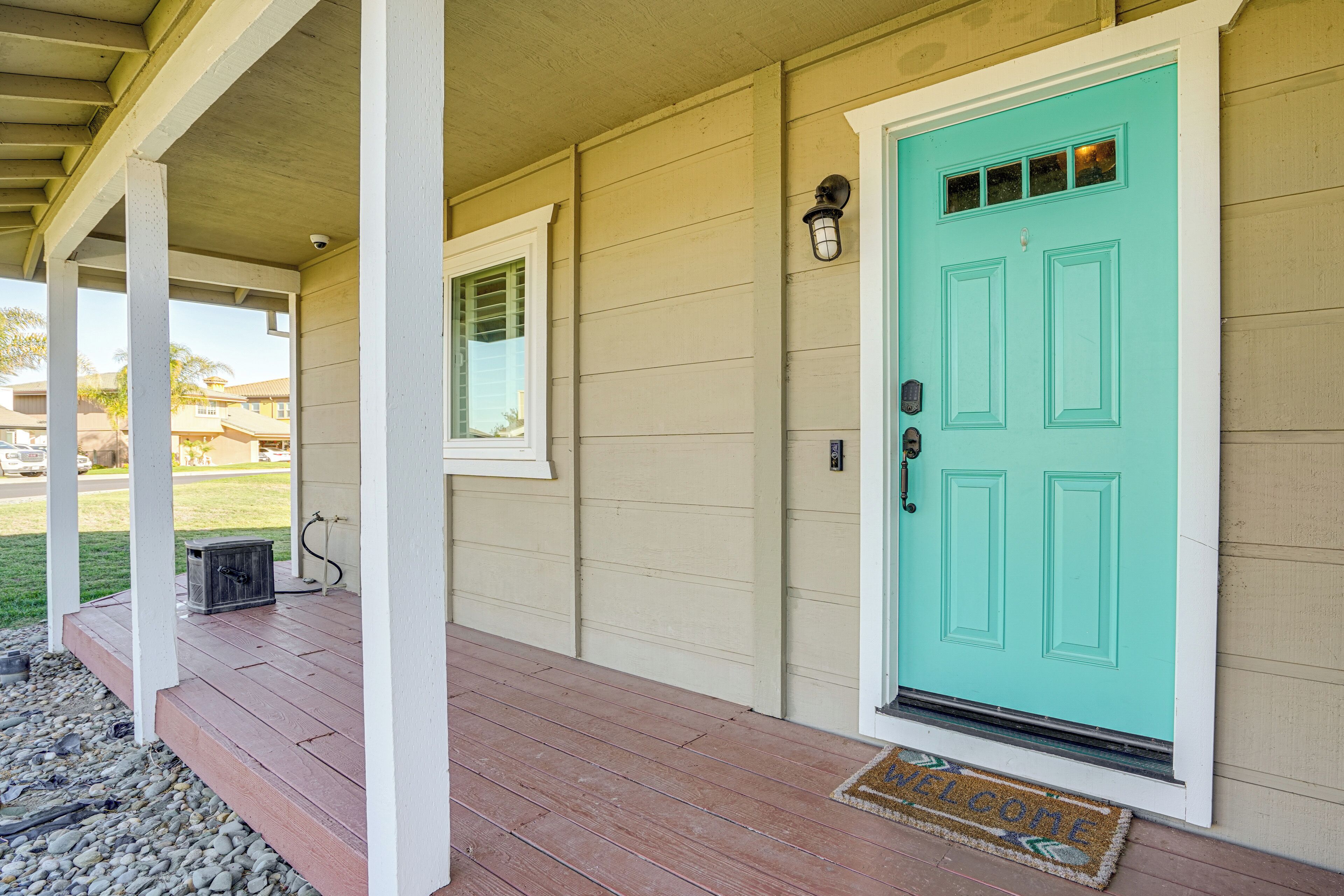 A house with a turquoise door, a porch with wooden steps, and a small window.