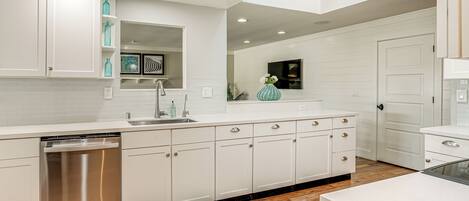 A modern kitchen with white cabinetry, a stainless steel dishwasher, and a built-in oven.