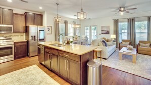 A modern kitchen with dark wood cabinets, stainless steel appliances, and pendant lighting. - Golf, Shop + Relax: Family Bluffton Home (Bluffton)