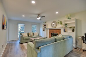 A living room with a fireplace, a ceiling fan, and a bookshelf. - Fully Updated! Suburb Stay Near Sugarloaf Mills (Lawrenceville)