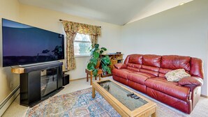 Ein Wohnzimmer mit Flachbildfernseher, Ledersofa, Couchtisch und einem gemusterten Teppich.