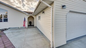 Eine Garage mit weißer Fassade, einer kleinen angebauten Veranda und einer amerikanischen Flagge.