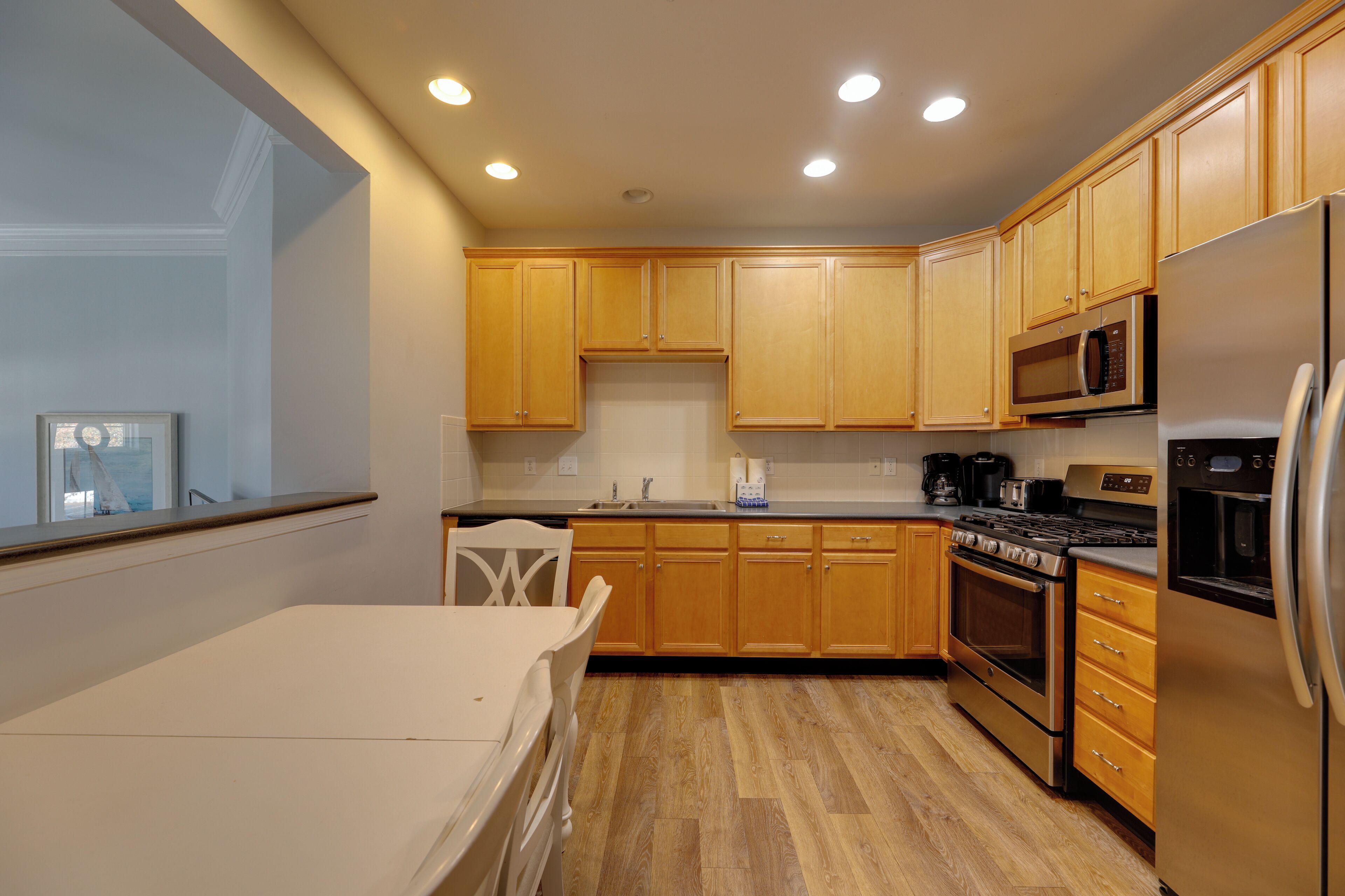 A modern kitchen with wooden cabinets, stainless steel appliances, and a window overlooking a balcony.